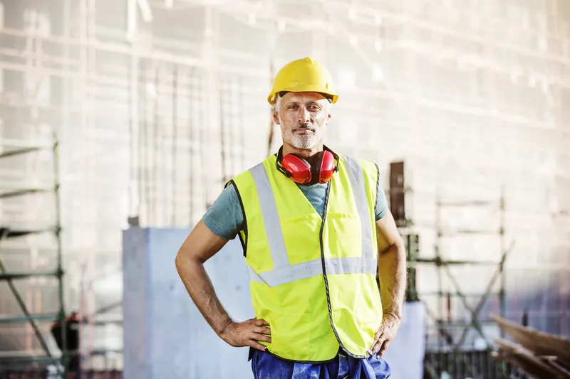 Site manager on a construction site holding a tablet showing trade weather advisories