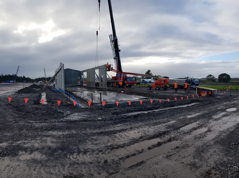 Crane operation above a waterlogged construction site in adverse weather