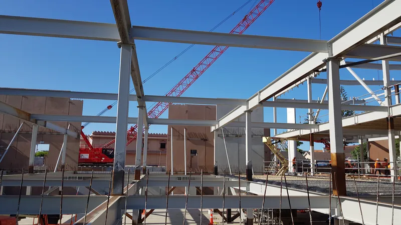 Site crew and crane working within a steel frame